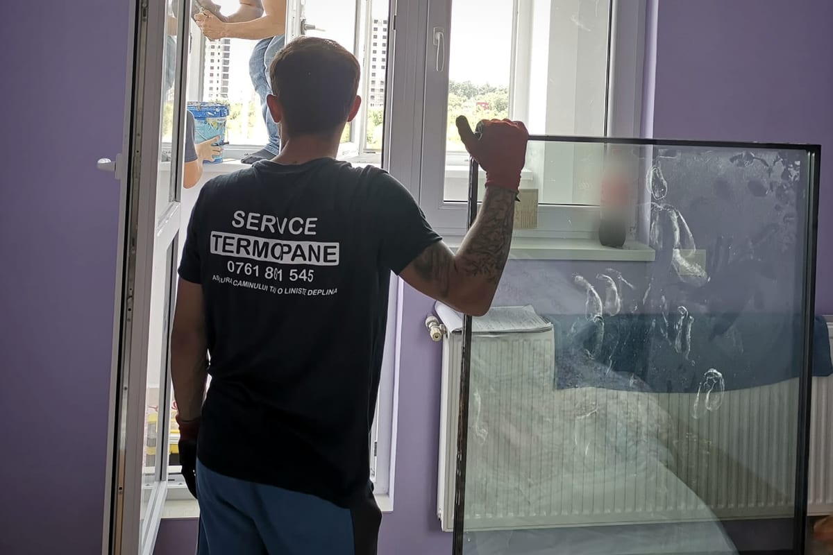 Tehnician cu un pachet nou de sticlă termopan, pregătit pentru montaj.